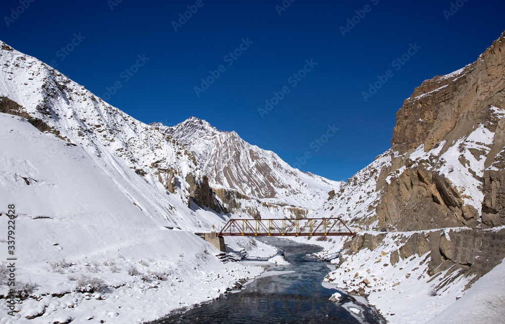  A bridge on Sipti river and beautiful snow covered mountains in Spiti valley of Himalayas.