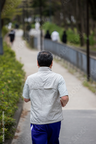 朝の公園でジョギングしている男性