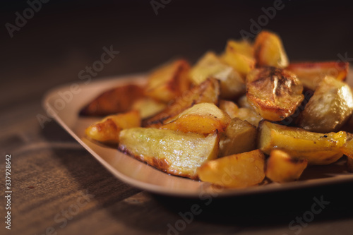 Baked crispy potatoes in a brown plate on a wooden table