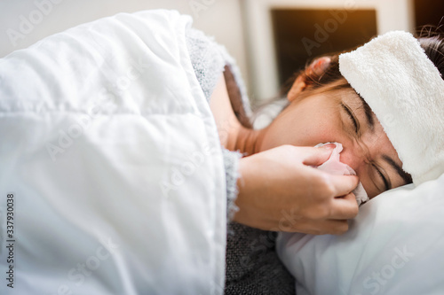 Sick asian woman have hight fever flu and sneezing into tissue on bed in bedroom, Healthcare and prevent the spread infection corona virus concept, Selective focus.