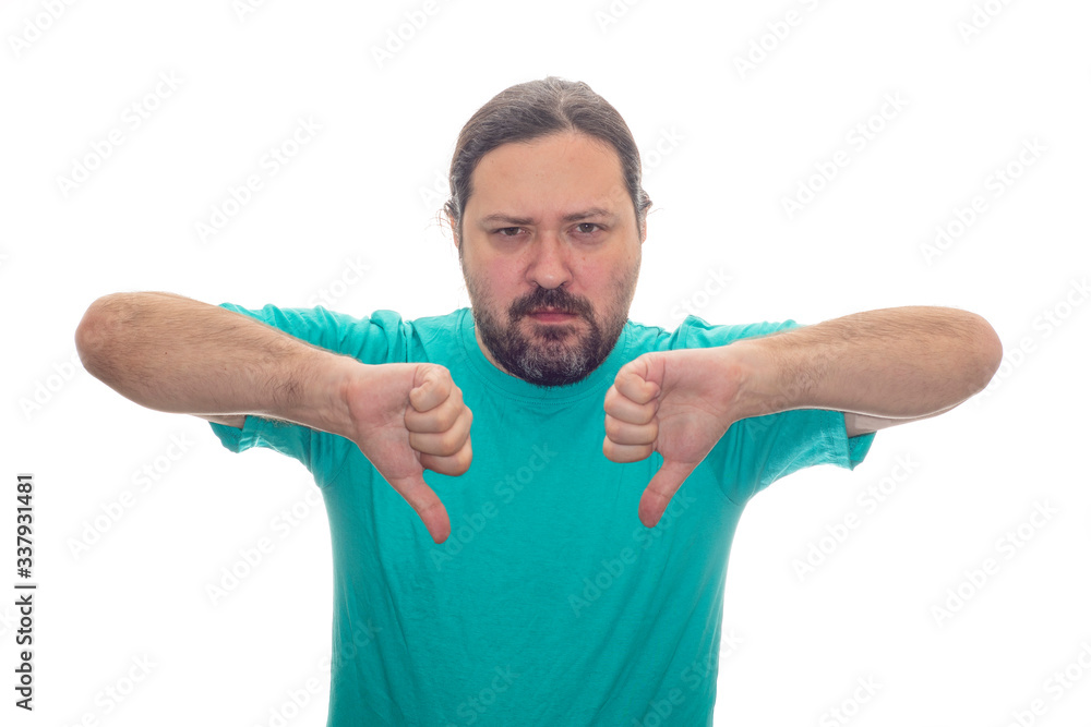 A frustrated, unshaven middle-aged man in a T-shirt shows a thumb down gesture. Isolated on a white background. A frustrated, unshaven middle-aged man in a T-shirt shows a thumb down gesture. Isolated on a white background.