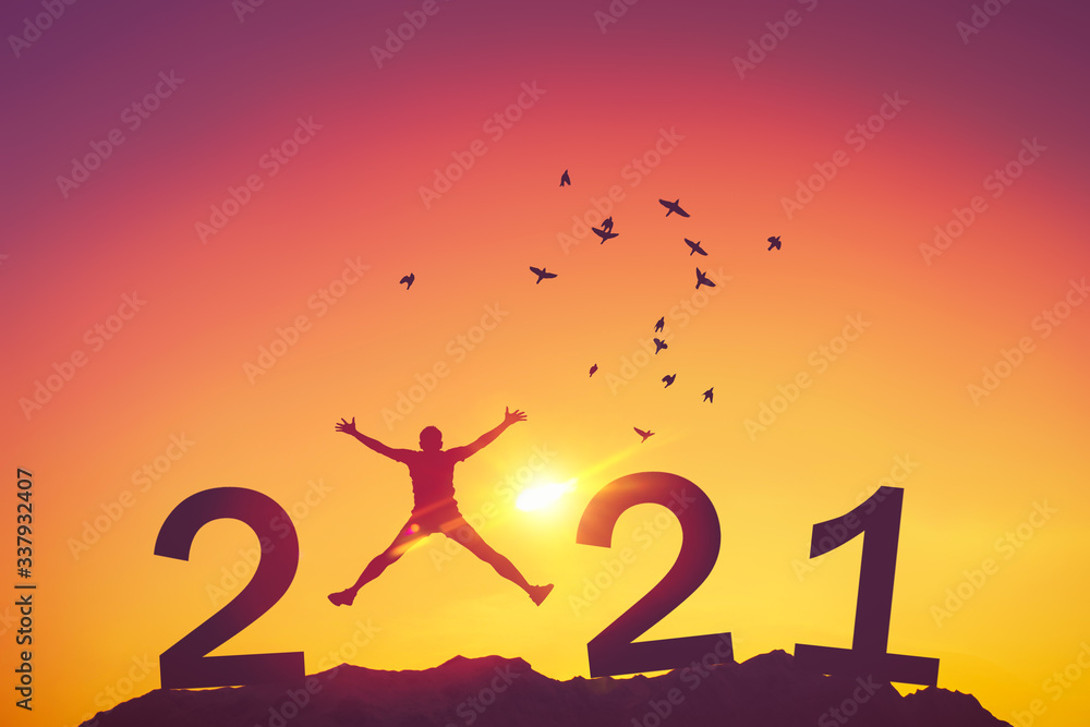 Silhouette man jumping and birds flying on sunset sky at top of mountain and number like 2021 abstract background. Happy new year and holiday celebration concept. Vintage tone filter color style.