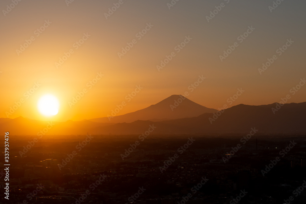 夕焼け・夕暮れ時、街並みの向こうに沈む太陽の夕日と富士山のシルエット