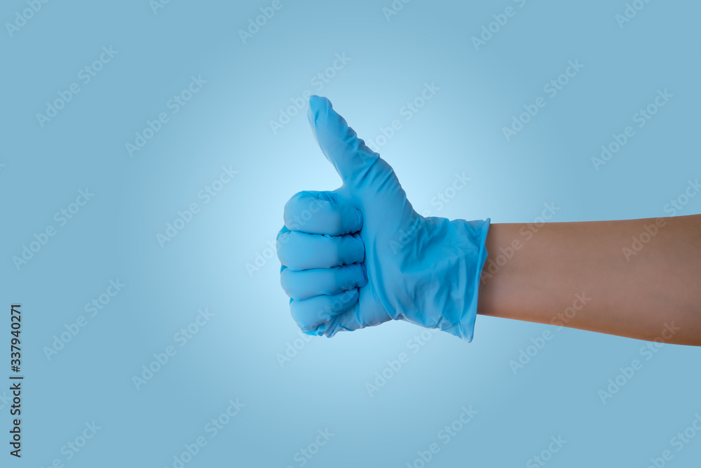 Hand with blue latex medical glove with thumb up showing OK sign
