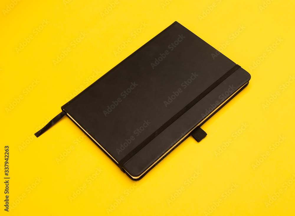 Black notebook isolated on yellow background. Black notebook isolated on yellow background.