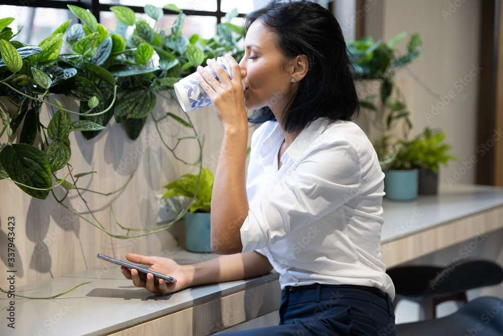 Young businesswoman drink coffee and using smartphone in coffee shop. Women relaxation coffee break, Lifestyle in city