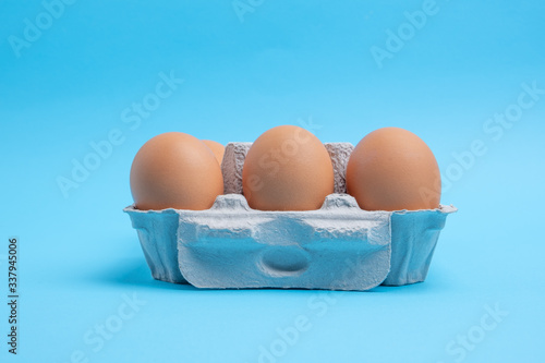 Side view of six pack of chicken eggs in carton on blue background with copy space photo