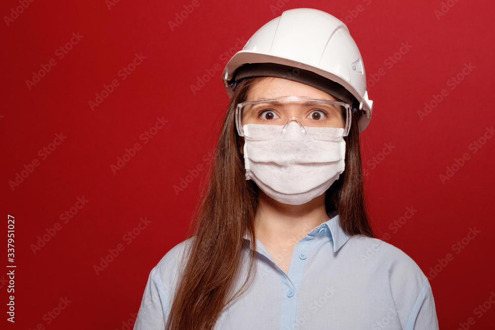 coronavirus pandemic, close-up portrait of young woman on red background in protective medical mask, builder architect in protective medical mask coronavirus pandemic, close-up portrait of young woman on red background in protective medical mask, builder architect in protective medical mask