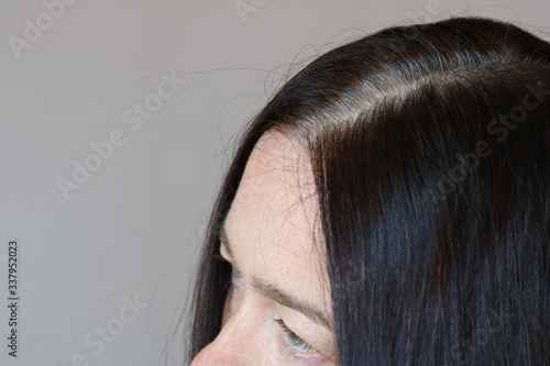 Middle aged woman serious and stressed effected to gray hair roots on white background.