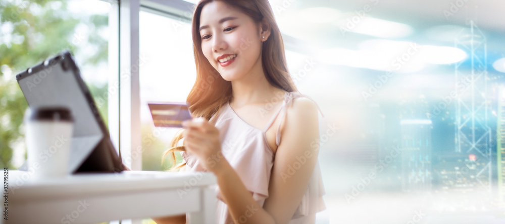 Happy Asian young woman doing online shopping at home.She holding credit card and using laptop computer.Smiling asian woman on couch using tablet to shop online n the living room. Happy Asian young woman doing online shopping at home.She holding credit card and using laptop computer.Smiling asian woman on couch using tablet to shop online n the living room.