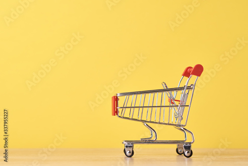 Empty shopping trolley cart on the yellow background. Shopping concept