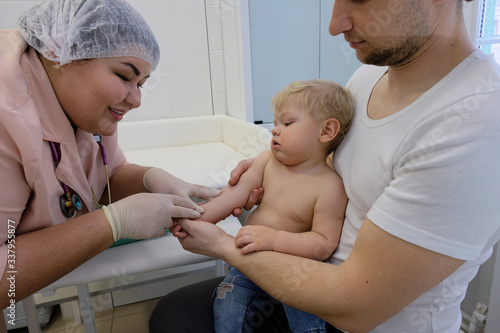 a nurse inoculates a little mulchik who came to see a doctor with his dad. viral infection vaccine COVID – 19