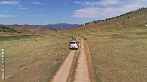 Aerial footage filmed with drone of pickup car riding in steppe. the car travels along the steppe to Siberia, roads laid along the Baikal island through the grassy hills.