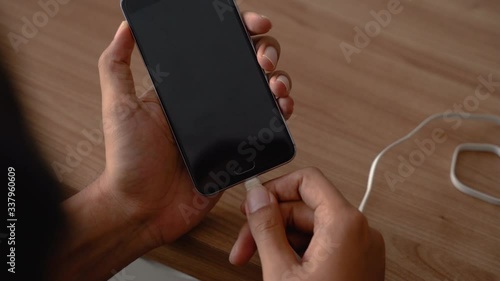 close up of hand charging smartphone plug in