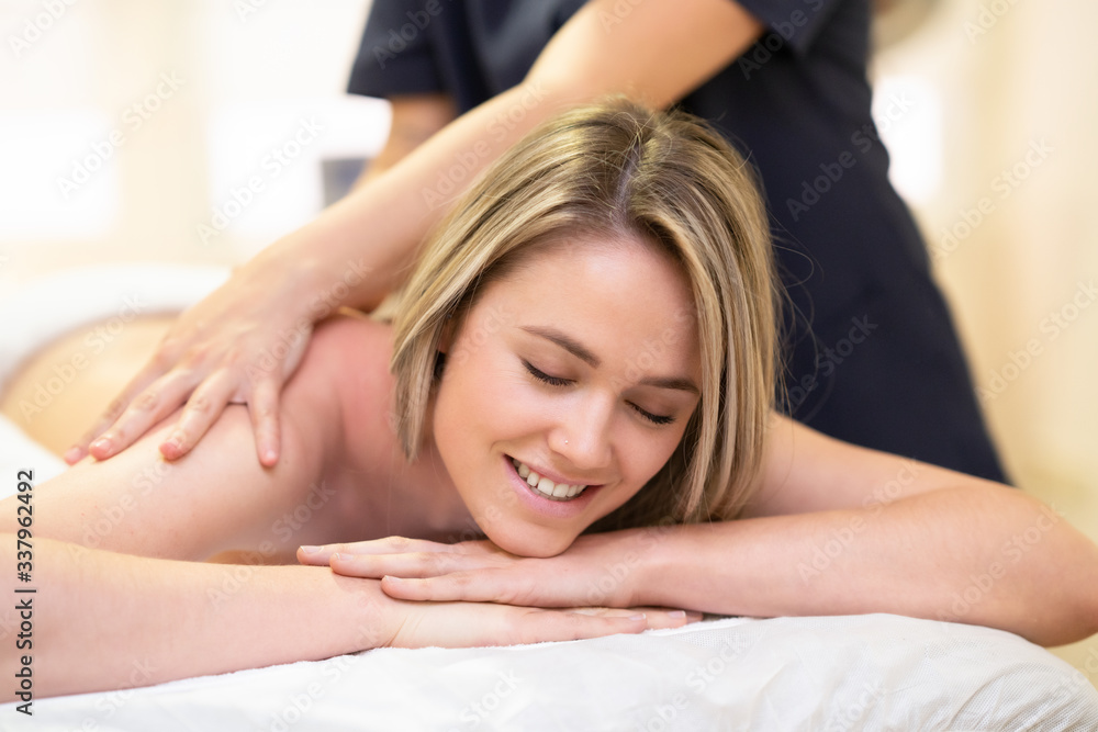 Obraz premium Woman lying on a stretcher receiving a back massage.