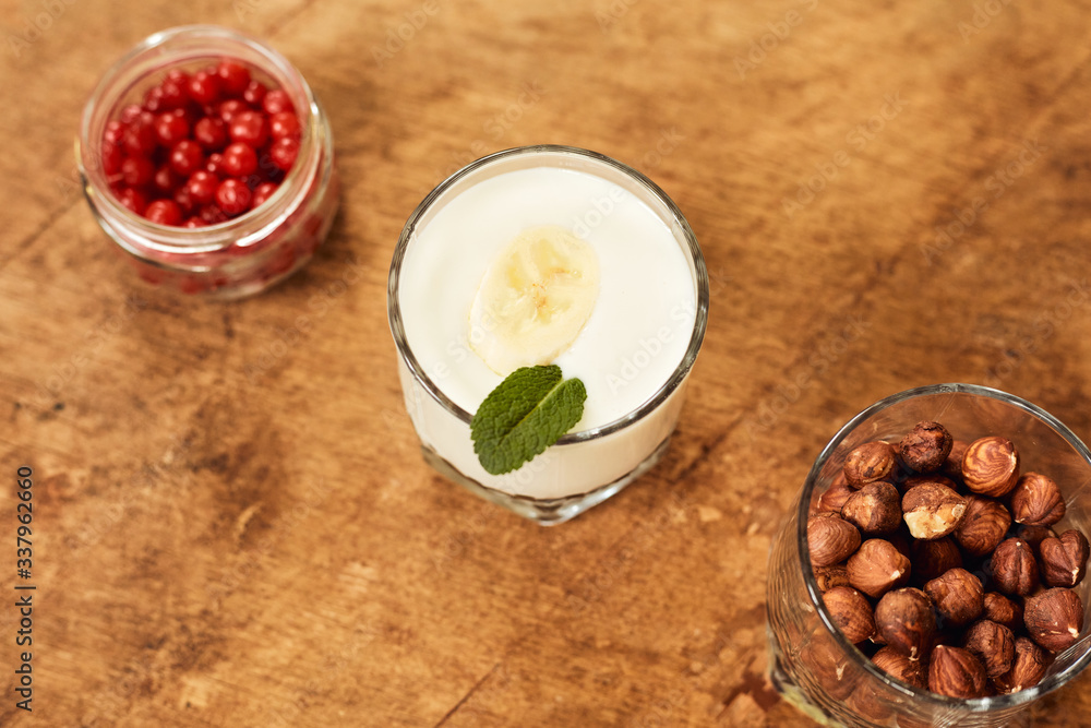 Yogurt with nuts on a wooden light background. View from above. Natural yogurt. Yogurt with nuts on a wooden light background. View from above. Natural yogurt.
