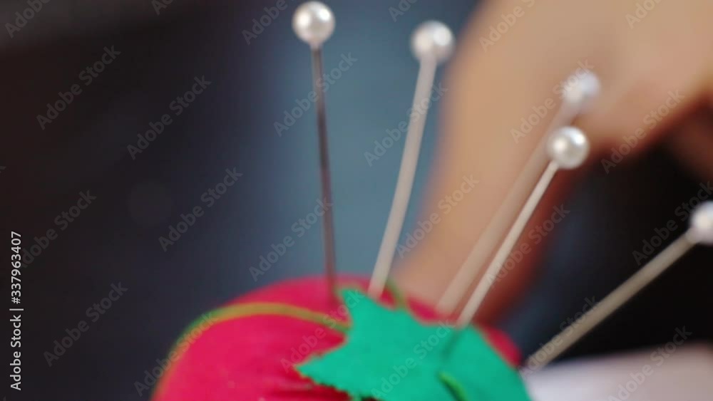 Woman grabbing pin from tomato pin cushion. Macro Woman grabbing pin from tomato pin cushion. Macro