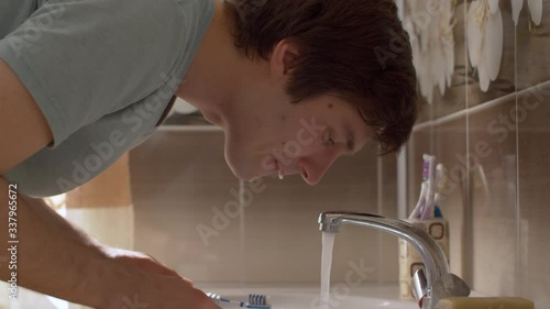 A man brushes his teeth in a beautiful bathroom. Close up young man rinses his mouth with water. Daily Hygiene Procedures