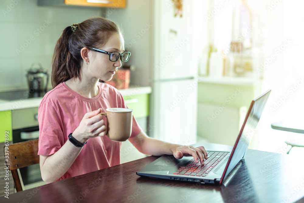 Woman remotely works on a laptop at home. Distance work and online education. Useful pastime when have to stay at home Woman remotely works on a laptop at home. Distance work and online education. Useful pastime when have to stay at home