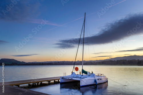 A small catamaran moored by the jetty at early evening.