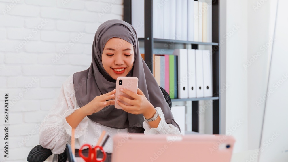 Asian muslim woman student or businesswoman waring hijab.Working from home with computer and smartphone.Concept of social distancing working alone at home in the epidemic situation of covid-19. Asian muslim woman student or businesswoman waring hijab.Working from home with computer and smartphone.Concept of social distancing working alone at home in the epidemic situation of covid-19.