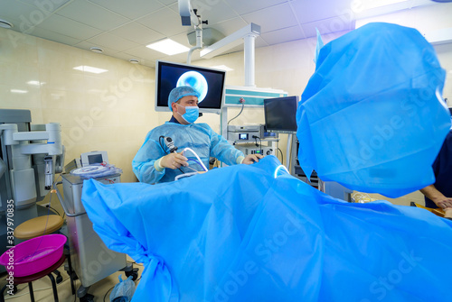 Group of doctors perform an operation to a patient. Surgeons in medical uniform and masks working in the operating room.