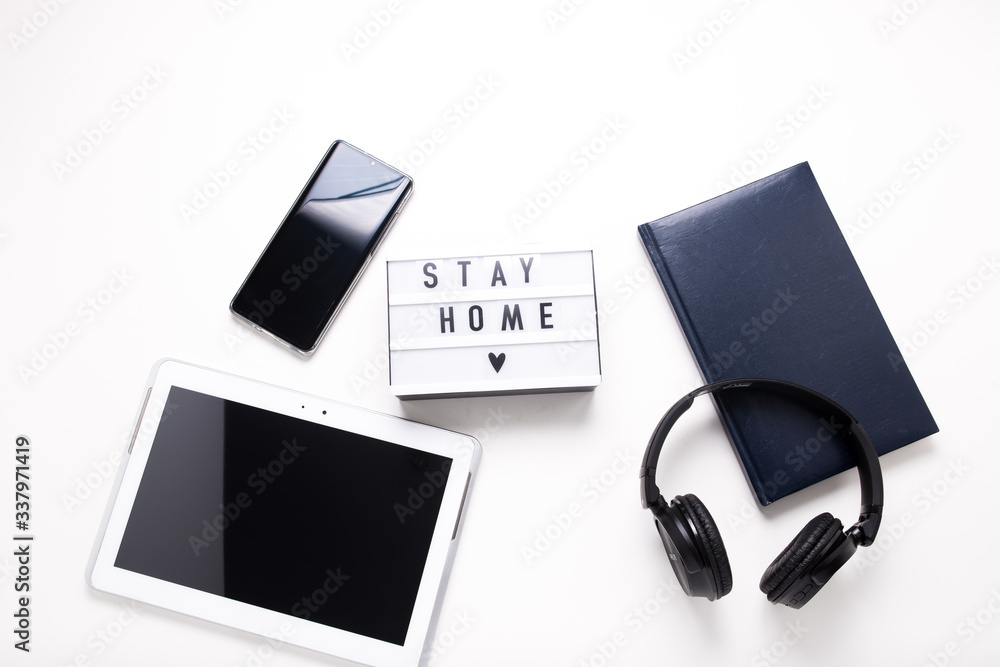Stay home, boxing inscription. Remote online work at home. Headphones tablet and diary on a white background. Stay home, boxing inscription. Remote online work at home. Headphones tablet and diary on a white background.