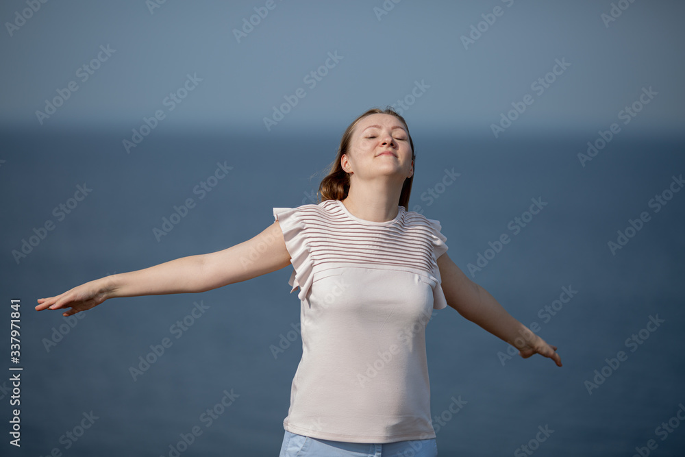 Woman relaxing at beach enjoying summer freedom with open arms and hair in the wind by the water seaside. Woman relaxing at beach enjoying summer freedom with open arms and hair in the wind by the water seaside.