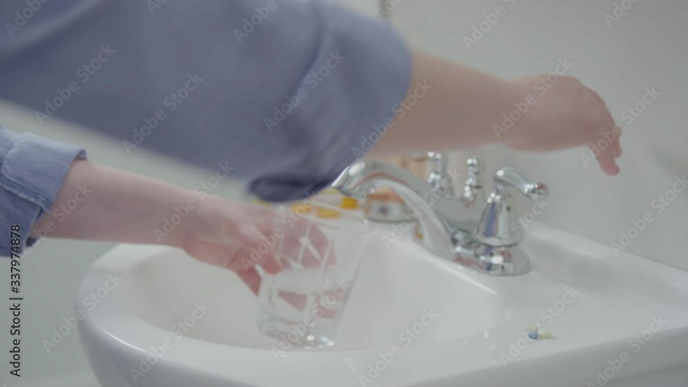 Side View Of Woman Filling Glass With Tap Water In Bathroom, She Takes Medication, Prescription Pill Bottles In Background Side View Of Woman Filling Glass With Tap Water In Bathroom, She Takes Medication, Prescription Pill Bottles In Background
