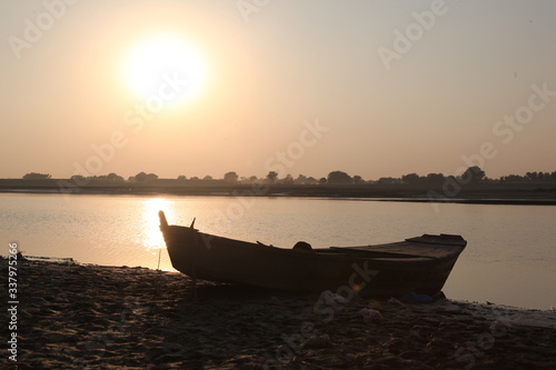 Old wooden boat at river shore with sunset. Old boat vintage look with sunset horizon in evening