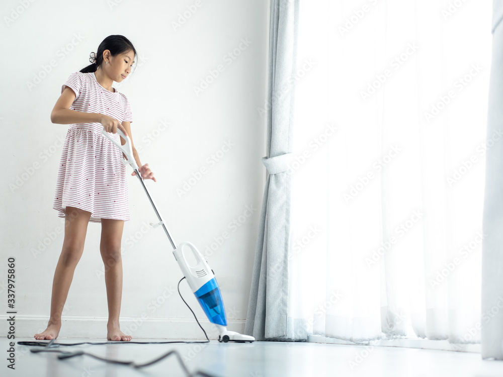 Asian girl using vacuum cleaner, girl standing near window at home during COVID-19. Asian girl using vacuum cleaner, girl standing near window at home during COVID-19.