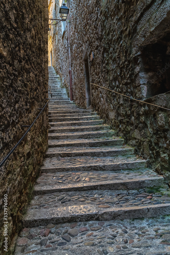 A narrow street in downtown of the medieval city of Girona, Spain. A narrow street in downtown of the medieval city of Girona, Spain.
