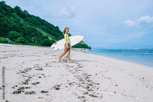 Happy female surfer standing on empty beach