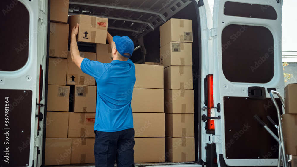 Courier Takes out Cardboard Box Package from Delivery Van Full of Parcels, Delivering Postal Parcel. Courier Takes out Cardboard Box Package from Delivery Van Full of Parcels, Delivering Postal Parcel.
