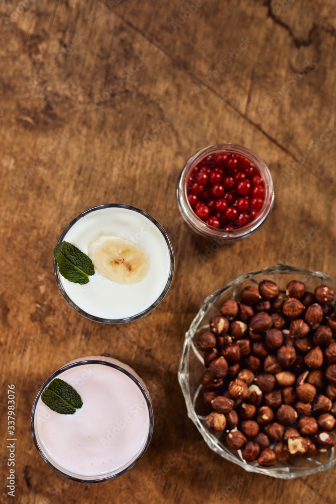Yogurt with nuts on a wooden background. View from above. Summer food. Yogurt with nuts on a wooden background. View from above. Summer food.
