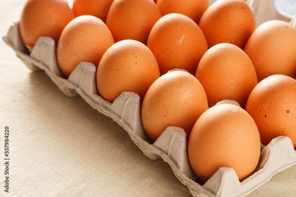 Raw organic brown chicken eggs in eco friendly paper carton on white kitchen wooden table Raw organic brown chicken eggs in eco friendly paper carton on white kitchen wooden table