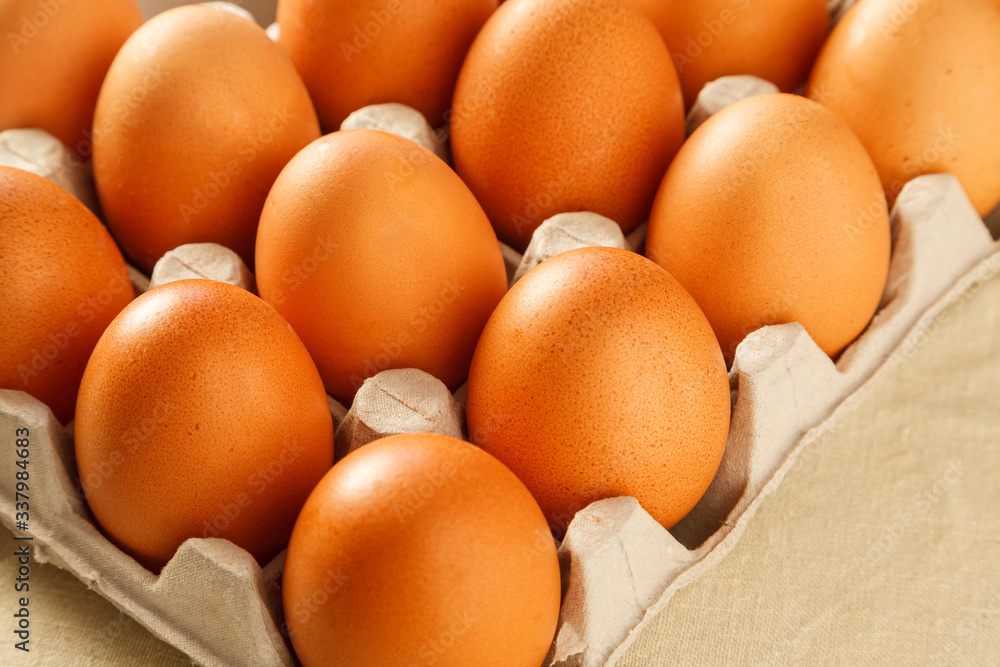 Raw organic brown chicken eggs in eco friendly paper carton on white kitchen wooden table Raw organic brown chicken eggs in eco friendly paper carton on white kitchen wooden table
