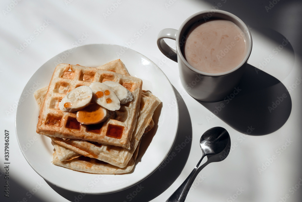 Cup of cocoa, toasts with jam and bananas on white plate