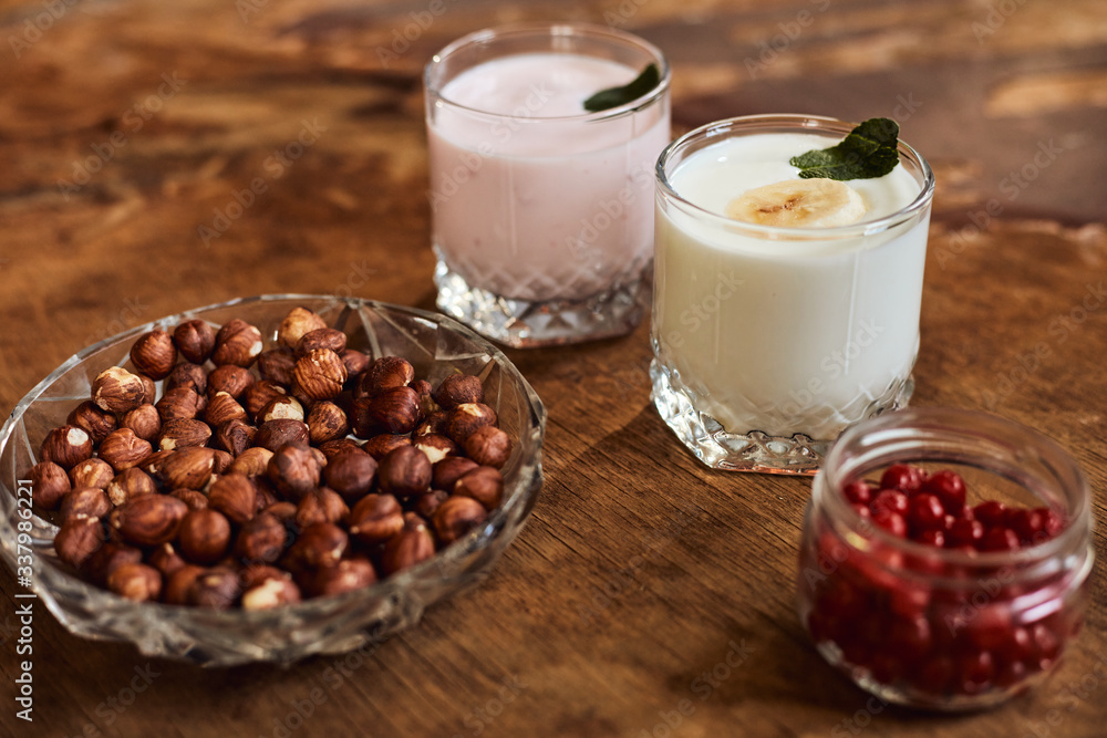 Yogurt with nuts on a wooden background. Side view. Summer food. Yogurt with nuts on a wooden background. Side view. Summer food.