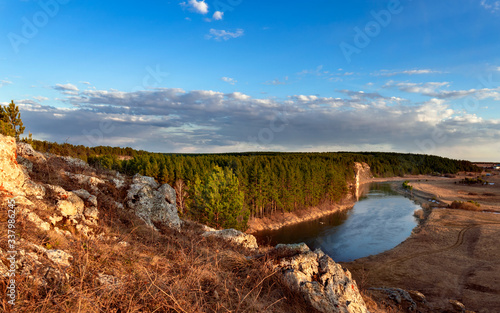 spring landscape. view from the cliff to the river enveloping the coniferous forest. beautiful blue sky and clouds