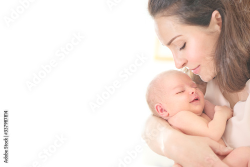 Mother and her Newborn Baby together. Love. Happy Mother and Baby kissing and hugging. High key soft image of Beautiful Family. Maternity concept. Parenthood. Motherhood, adoption concept