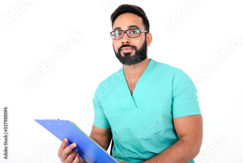 Handsome young paramedic (nurse) sitting with medical records in his hands and happily smiling, isolated on white background photo