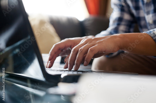 Hand of a man typing a laptop computer keybord to sending an email or communication with customer at home office.