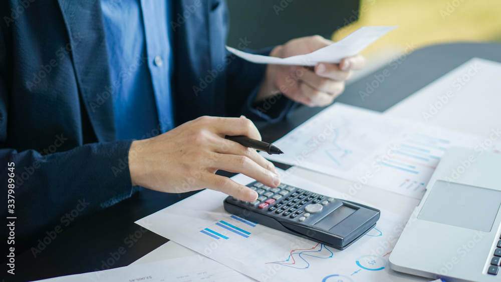Businessman with bills and calculator. Young male checking balance and costs. Start up counting finance. Business people doing paperwork for paying taxes Businessman with bills and calculator. Young male checking balance and costs. Start up counting finance. Business people doing paperwork for paying taxes