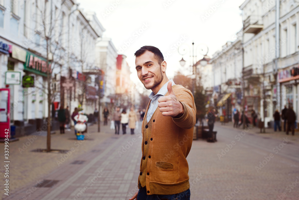A young dark man stands in the middle of the street and shows his thumb up. A young dark man stands in the middle of the street and shows his thumb up.