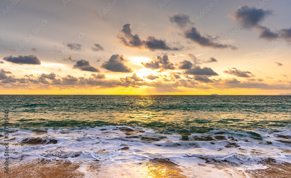Beautiful sunset above sea or ocean. Vibrant and soft colors, magic light. Small clouds on the sky, reflection of sun in the water and sand on beach. Concept of romantic time on vacation in tropical.