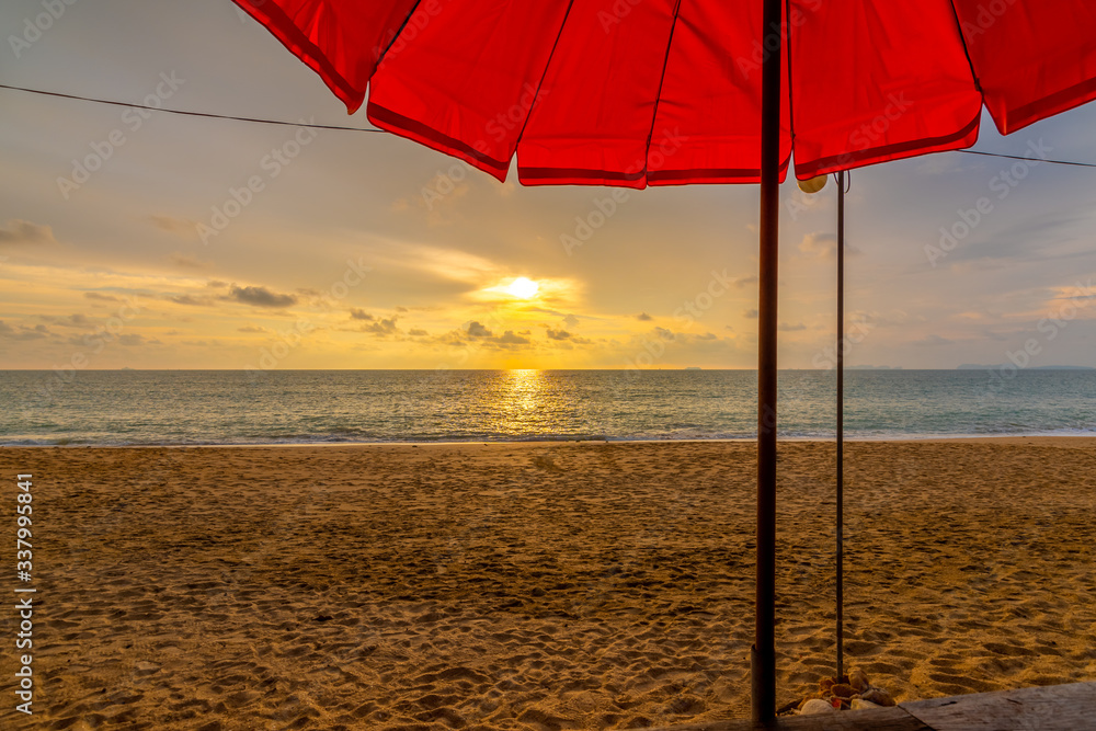 View of the beautiful sunset above beach at Koh Lanta island, Thailand. Look from the shadow of beach umbrella. Vibrant and soft light, colorful concept of relaxation and vacation time in tropical.