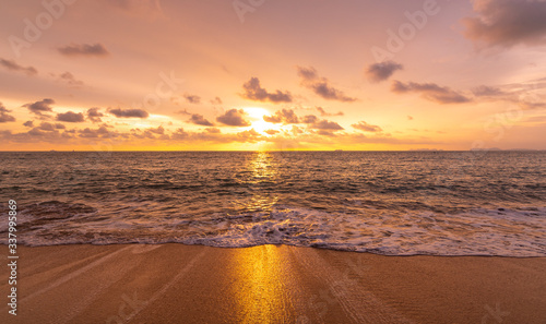 Fototapeta Naklejka Na Ścianę i Meble -  Beautiful sunset above sea or ocean. Vibrant and soft colors, magic light. Small clouds on the sky, reflection of sun in the water and sand on beach. Concept of romantic time on vacation in tropical.