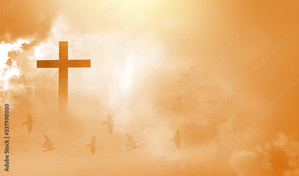 The Christian cross looks bright in the golden sky, with soft white clouds and beautiful light which leads to peace and heaven.