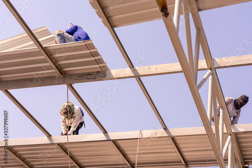 Εκτύπωση καμβά Three men are installing the roofing sheet on Light steel Truss and Frame construction